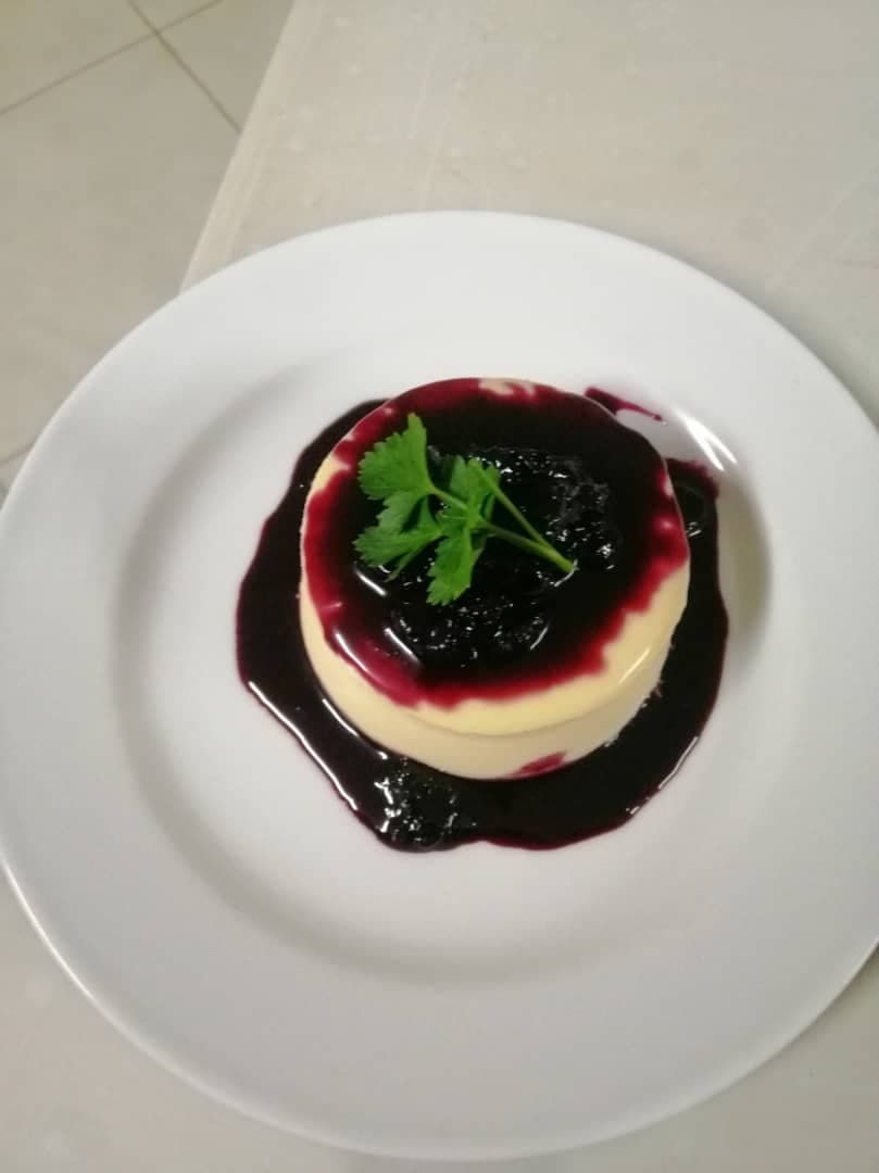 A round cheesecake finished with dark berry coulis and a sprig of herb