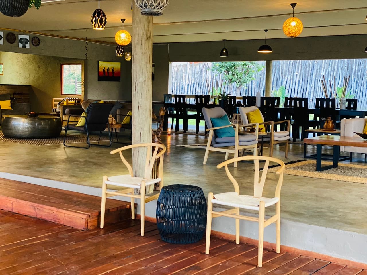 The lounge at Xhabe Safari Lodge, open on two sides to the bush, with wishbone chairs on a wooden deck