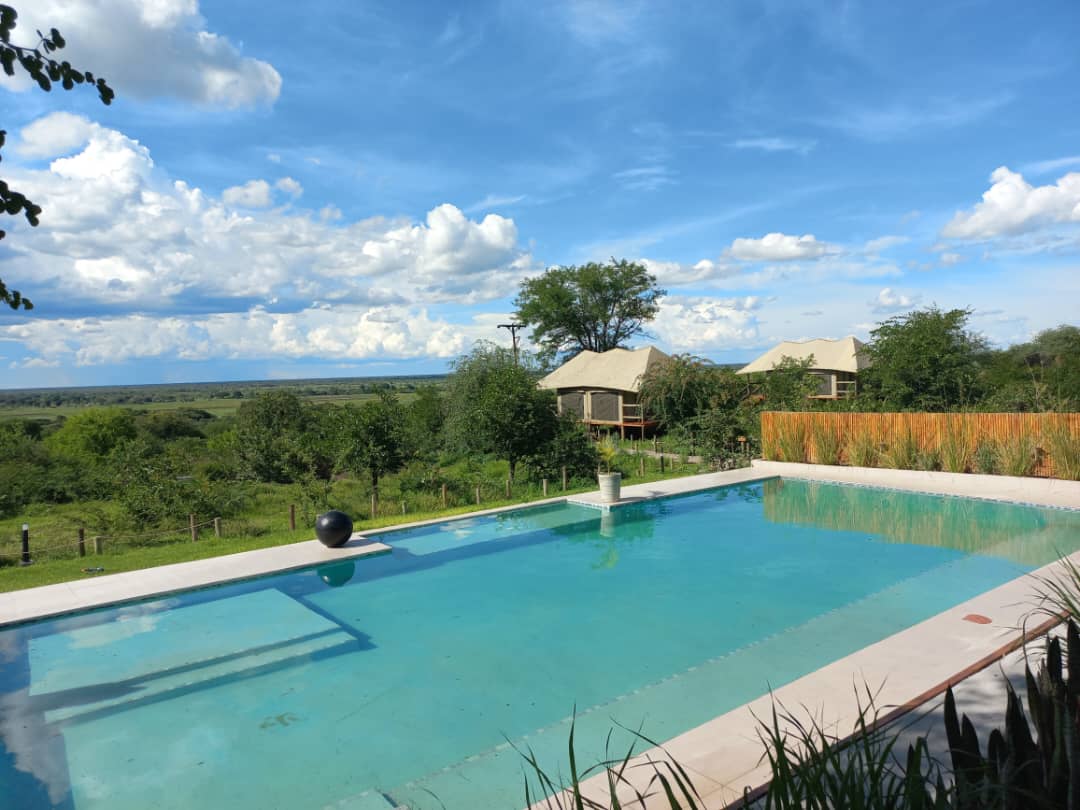 The swimming pool at Xhabe Safari Lodge with two tented chalets and the Chobe floodplain beyond
