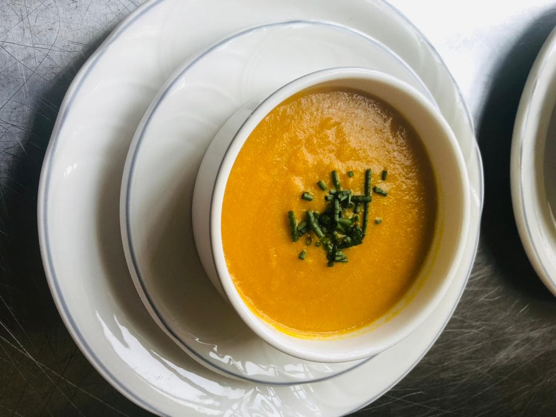 A bowl of butternut soup topped with chopped chives