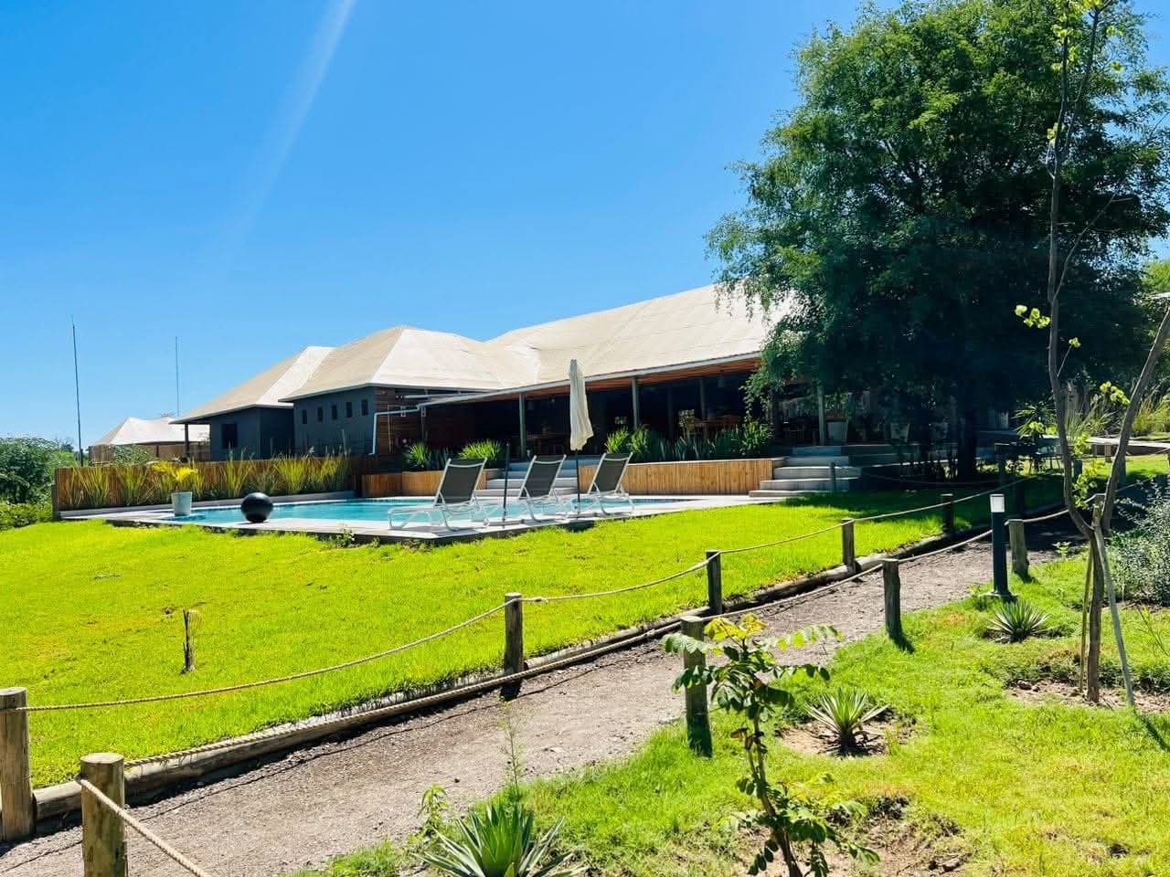 The main building and pool at Xhabe Safari Lodge seen across the lawn on a clear day